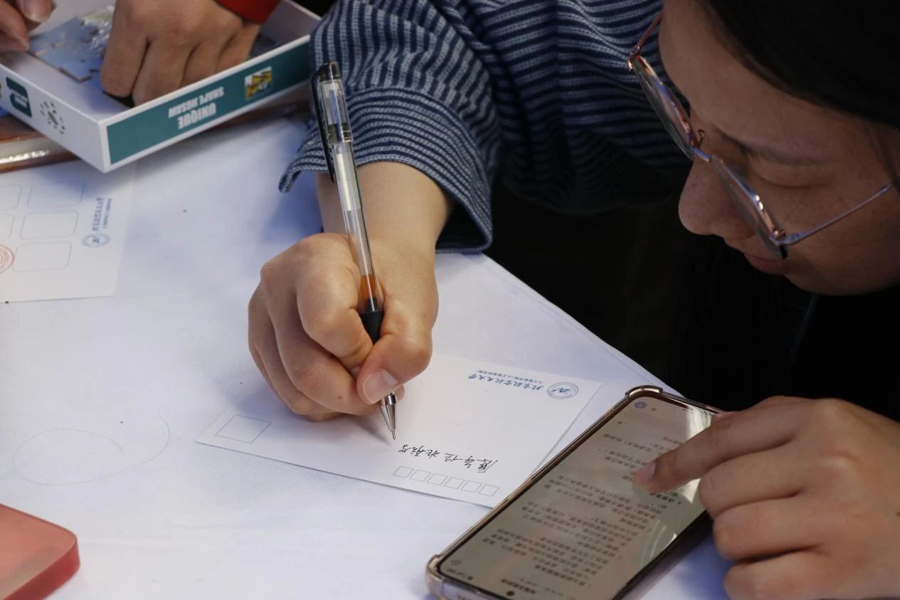 同学们在明信片上认真书写着对母校的深
